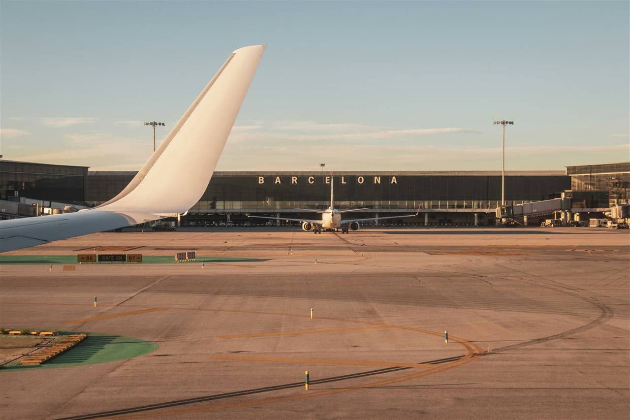 Terminal des Flughafens Barcelona mit dem Schriftzug BARCELONA und ein Flugzeug auf dem Vorfeld