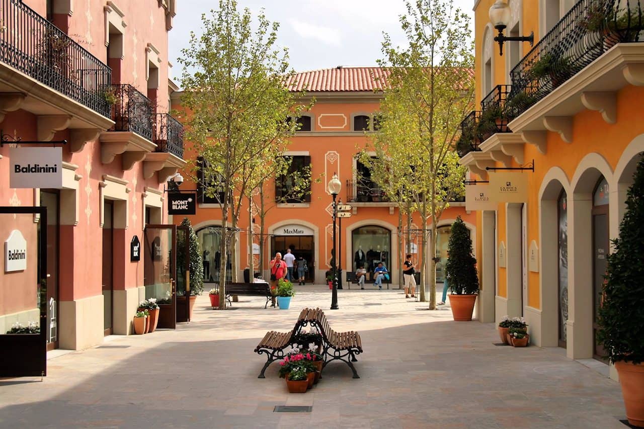 Plaça de l'outlet amb un banc i flors