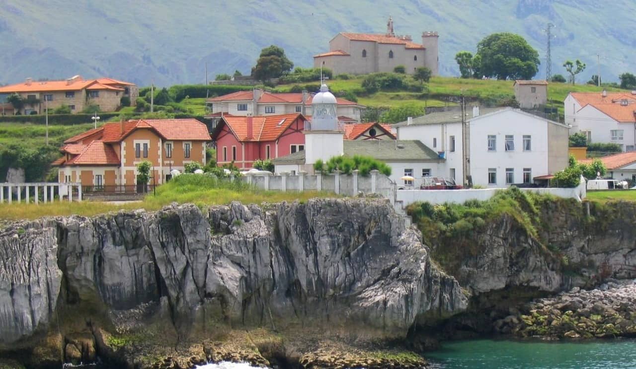 El far de Llanes damunt la roca, a l'entrada del port