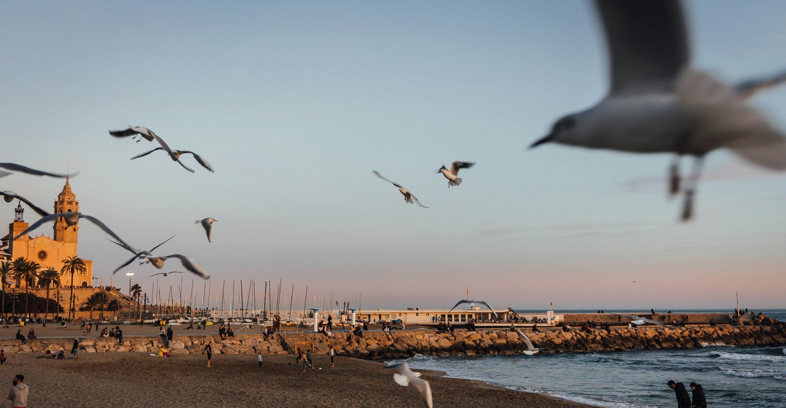 Sitges beach at sunset with the church and the marina in the distance