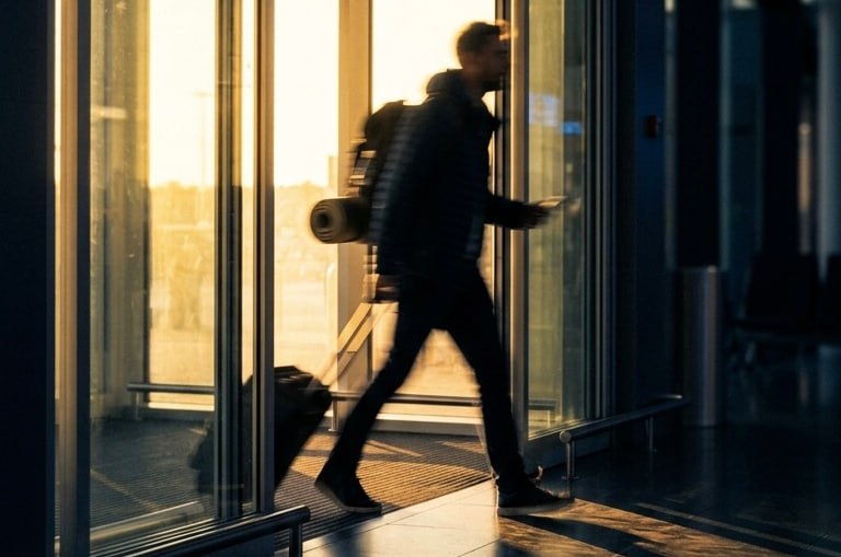 A passenger with a backpack walking out of the terminal at sunset