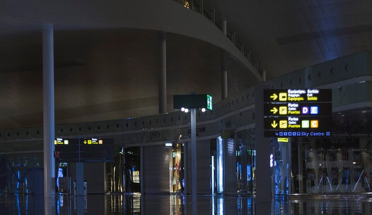 Vestíbulo de la terminal del aeropuerto de Barcelona con señales hacia las puertas