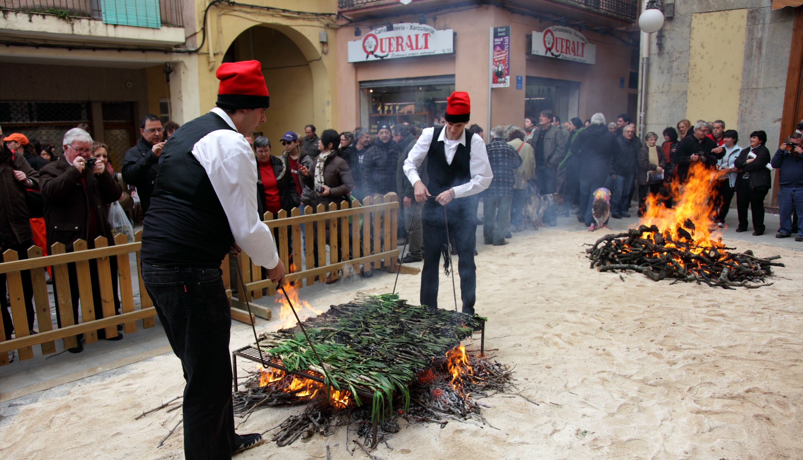 Cocineros con barretina asando calçots en la plaza de Valls