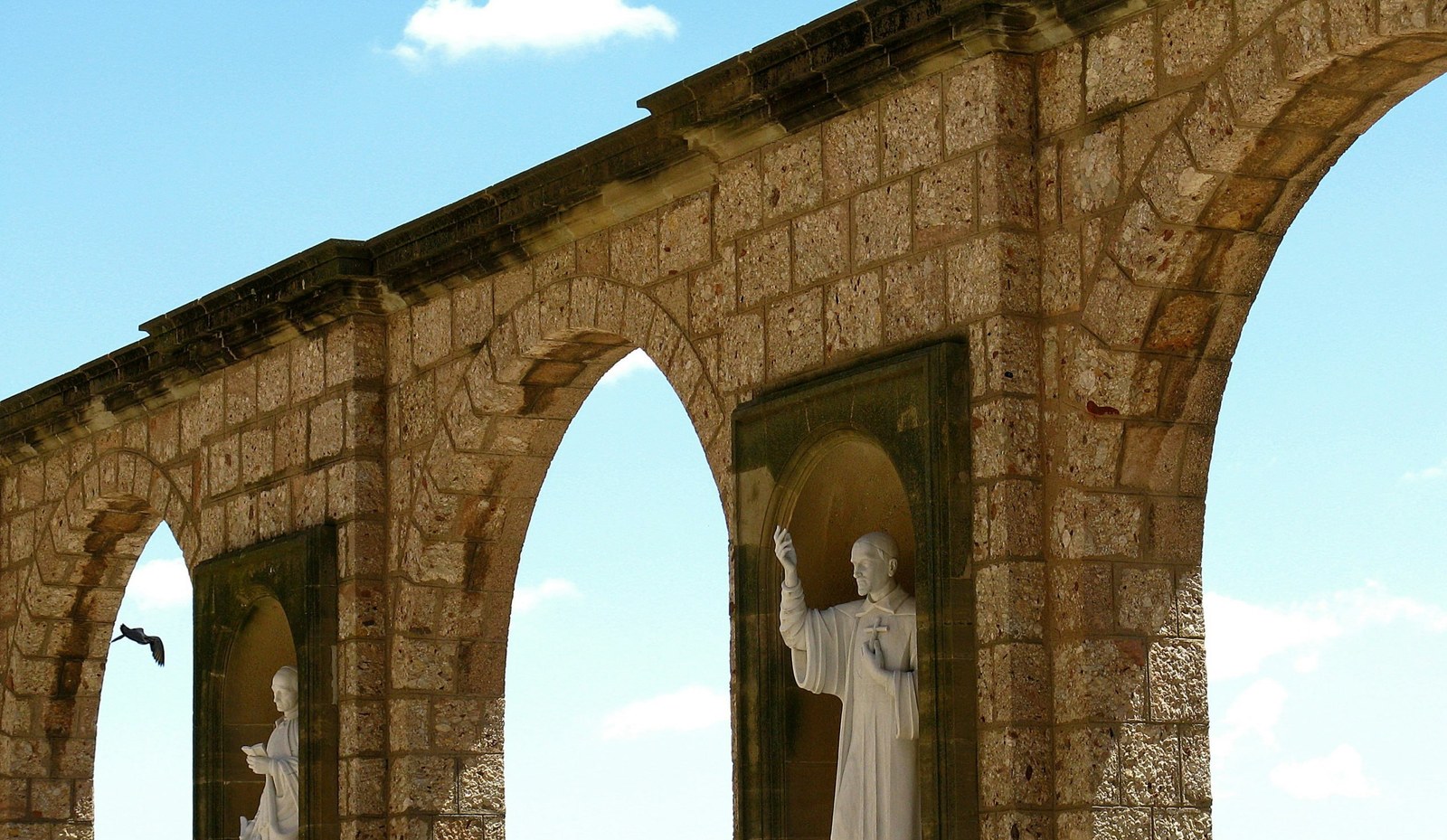 Estatuas blancas entre arcos de piedra sobre el jardín, en Blanes