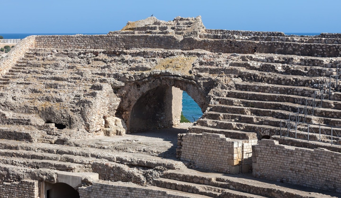 Gradas del anfiteatro romano de Tarragona, con el mar asomando por un arco