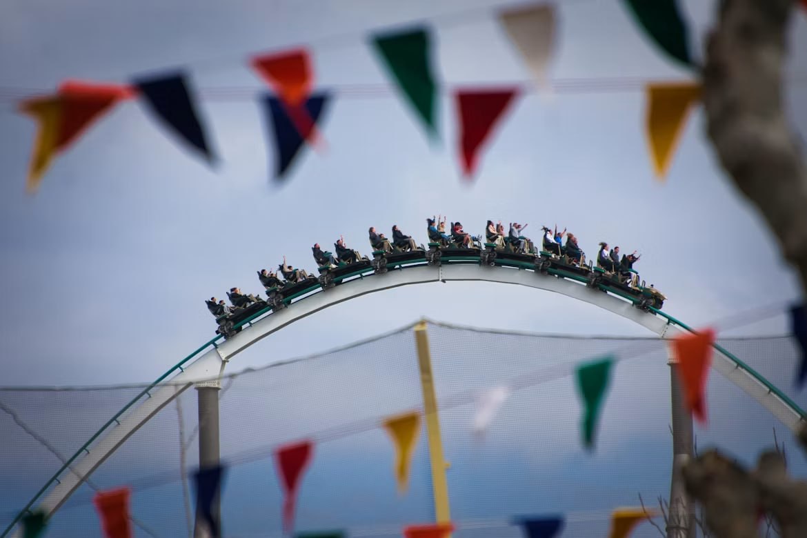 Un tren de muntanya russa al punt més alt de l'arc sobre els banderins de festa