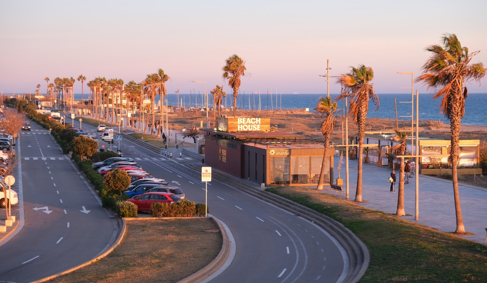 Castelldefels promenade at sunset: palms, beach and sea beyond the dunes