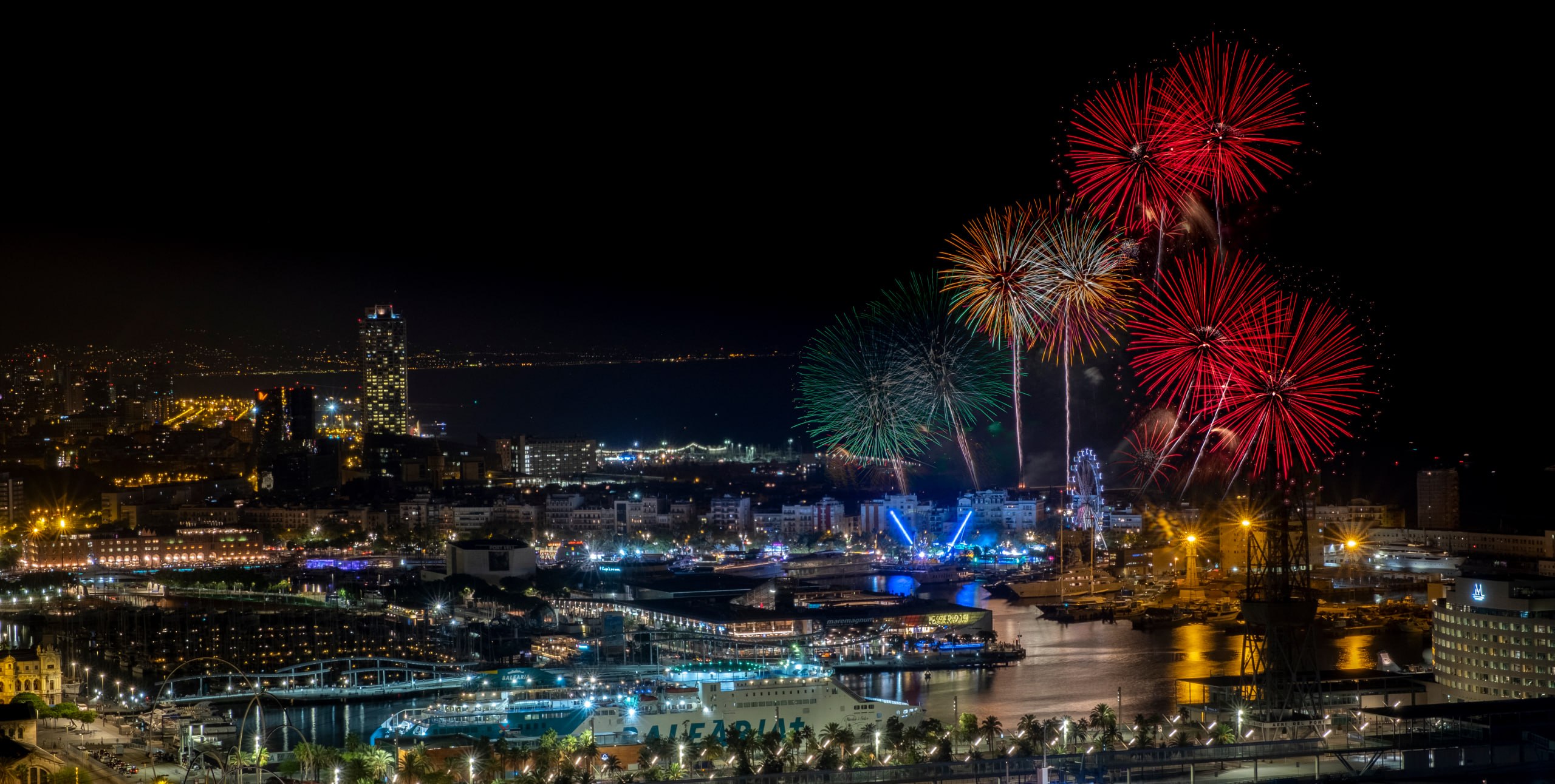 Piromusical über Barcelona: Feuerwerkssalven über dem Hafen und der beleuchteten Stadt