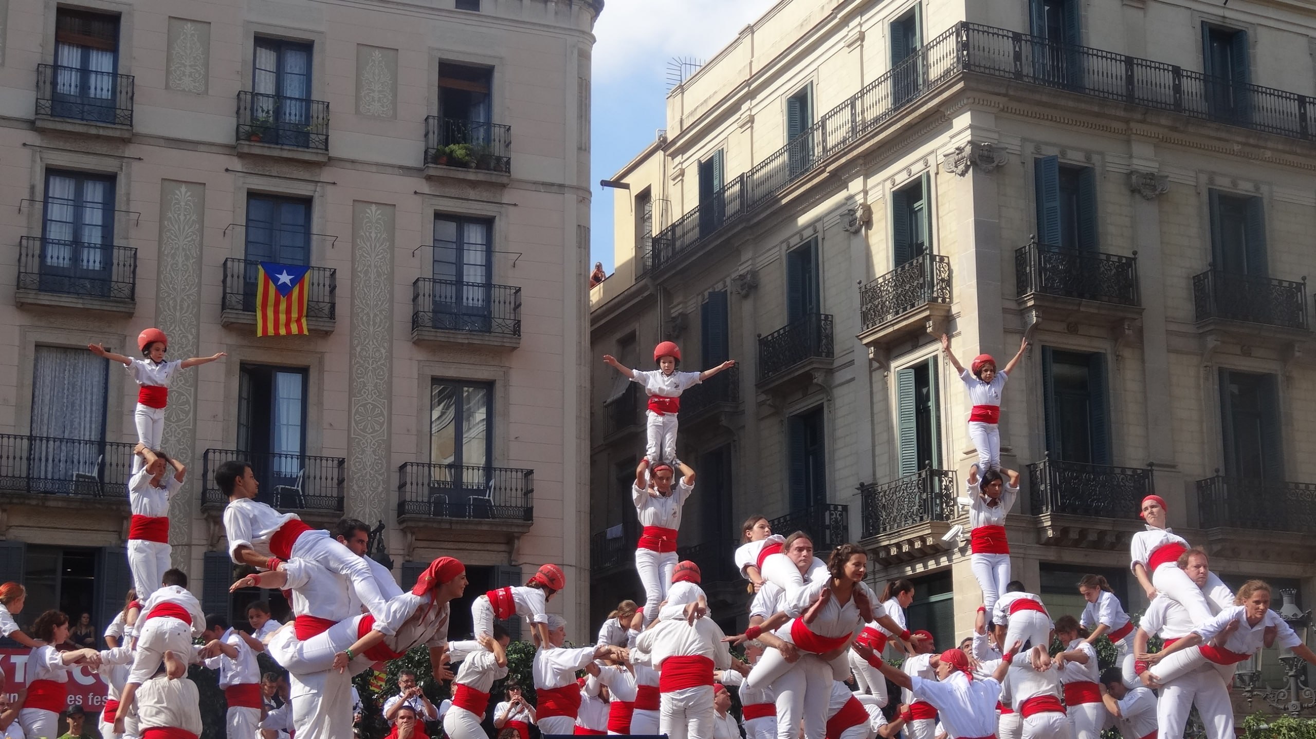 Castells auf der Plaça Sant Jaume: Kinder mit roten Helmen auf der Spitze eines Menschenturms