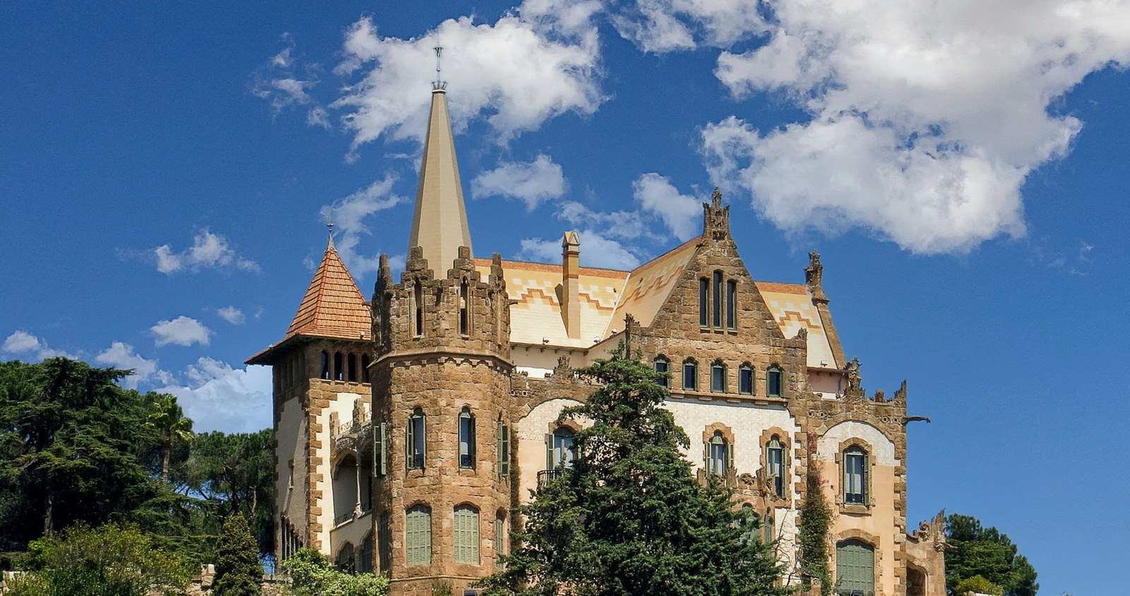 Casa El Pinar al vessant del Tibidabo: torre amb agulla i parapet emmerletat sobre les palmeres