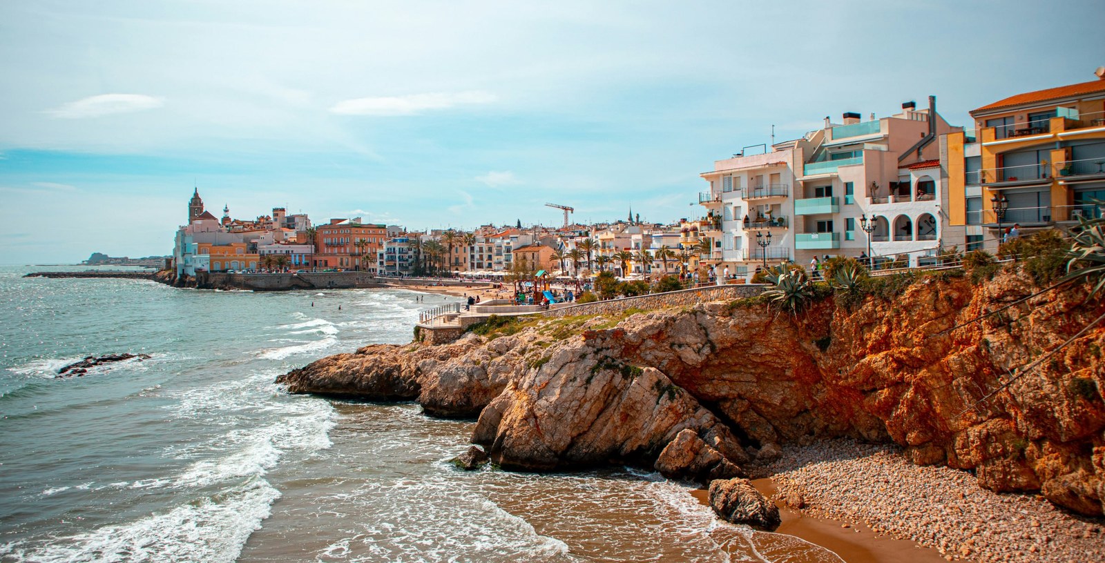 El litoral de Sitges: el nucli antic sobre el cap, l'església sobre el mar i les roques vora l'aigua