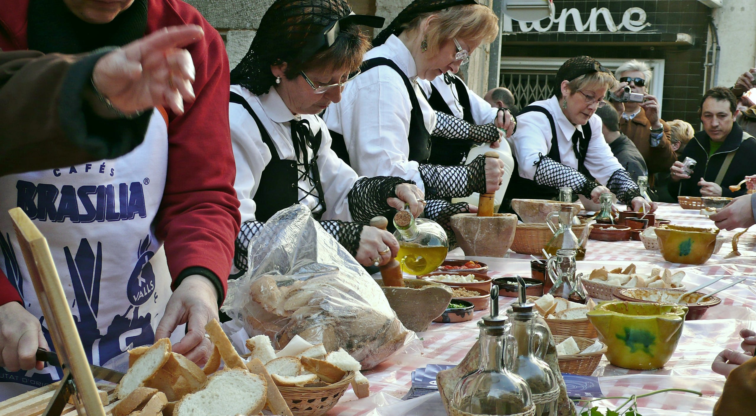 Mujeres con traje tradicional preparando salsa romesco en una mesa común
