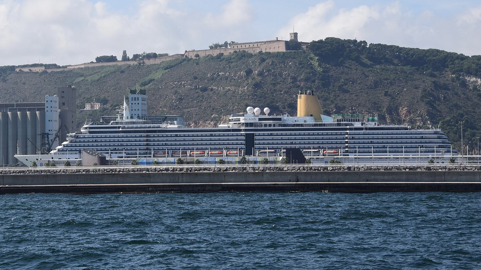 A cruise ship berthed at the Port of Barcelona below Montjuic