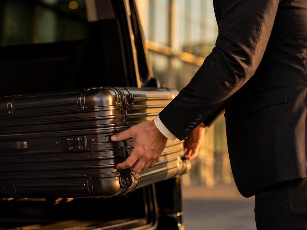 Driver loading a suitcase into the car