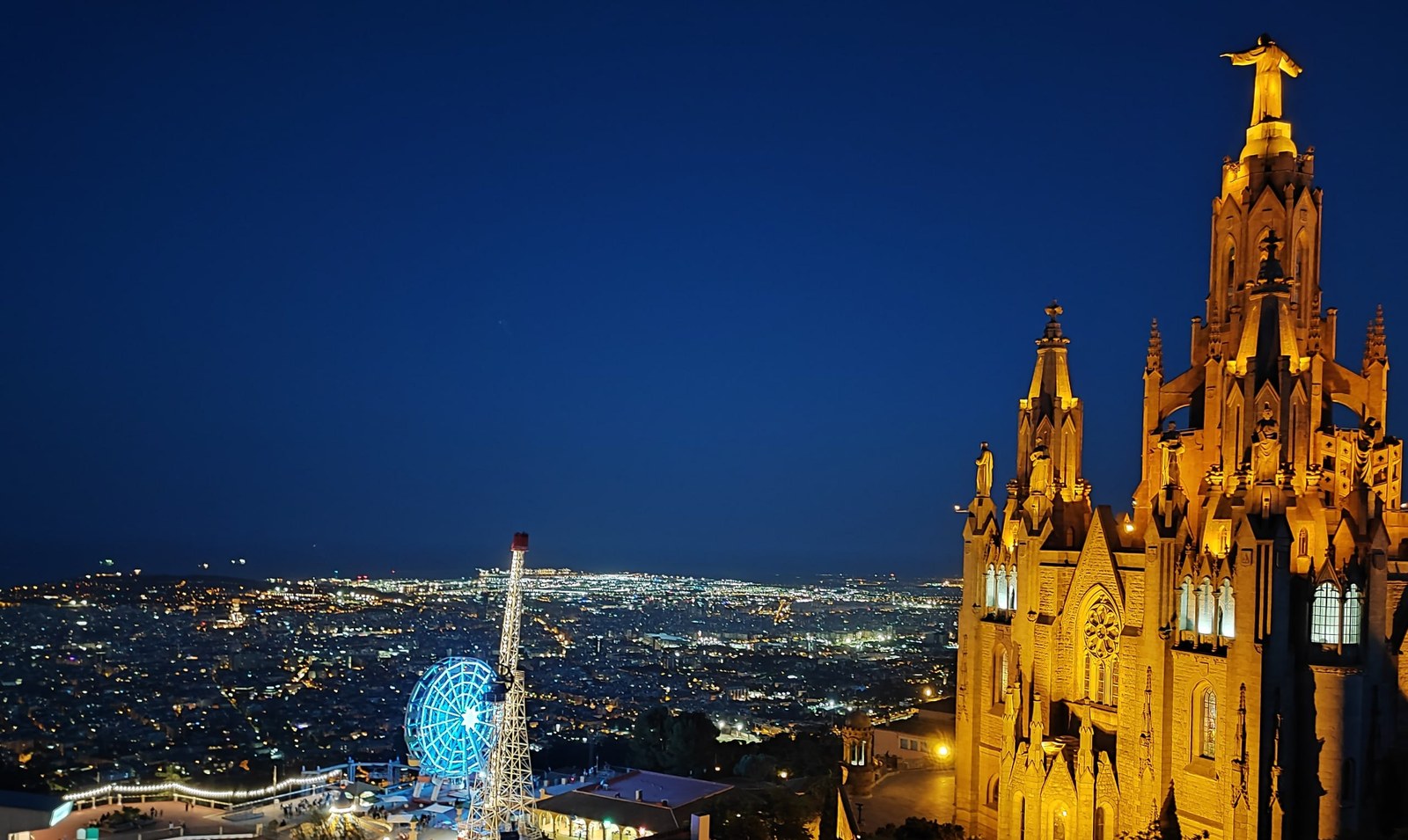 The Temple of the Sacred Heart and the Ferris wheel of Tibidabo park at night above the lights of Barcelona