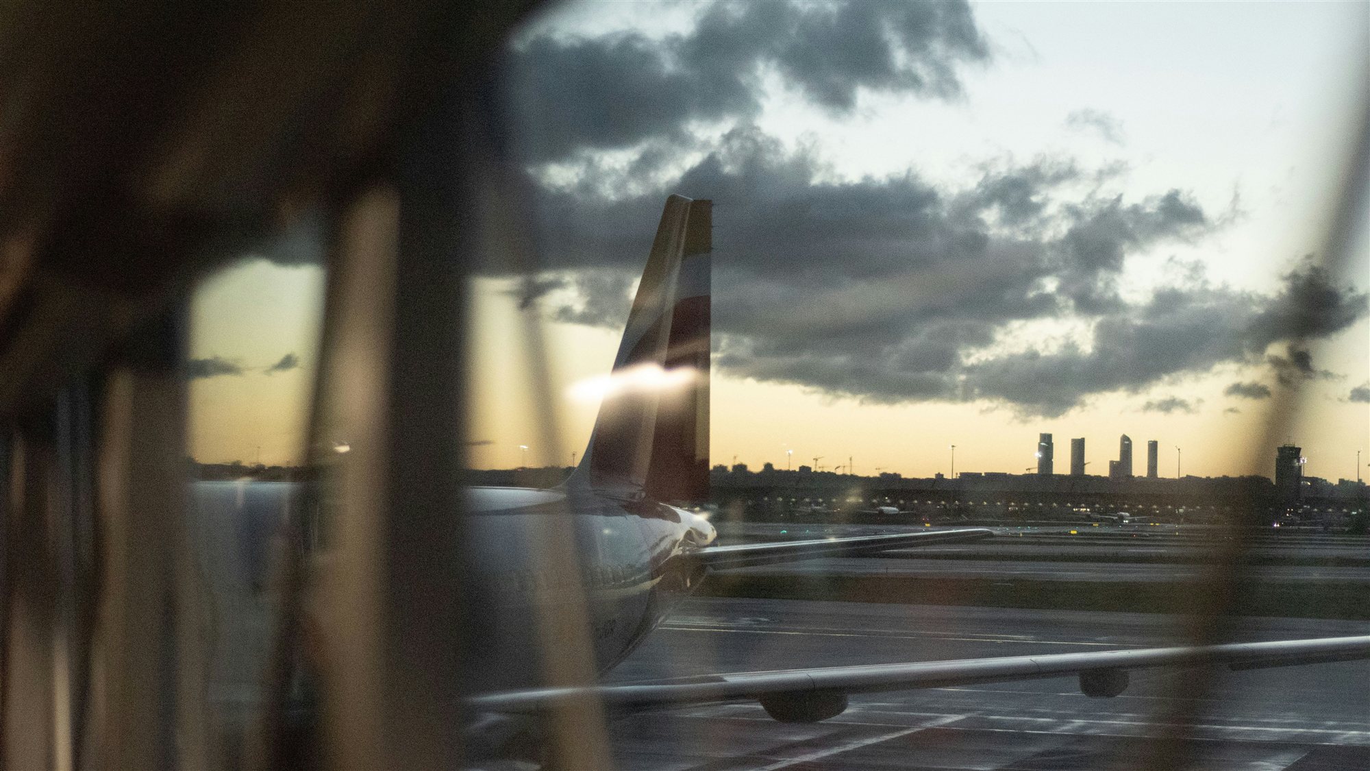 Avió davant d'una terminal de Barajas al capvespre, amb els gratacels de Madrid a l'horitzó