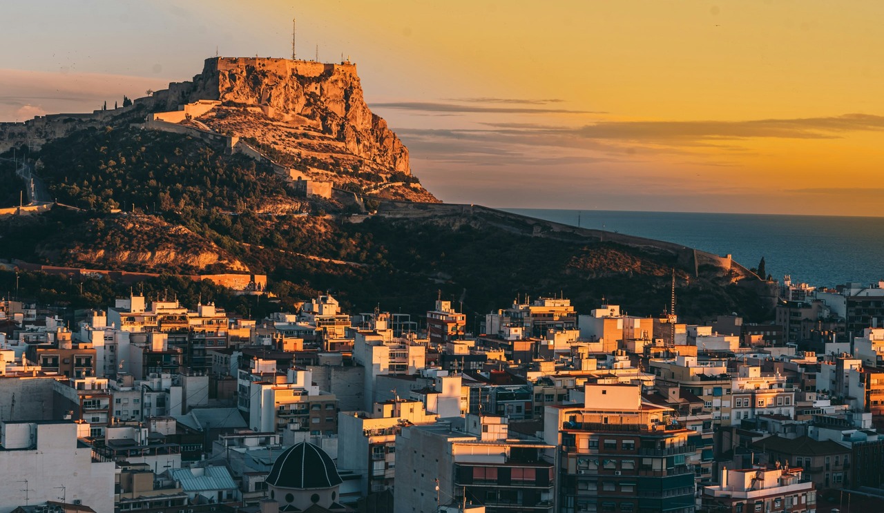El castell de Santa Bàrbara al capvespre sobre les teulades d'Alacant