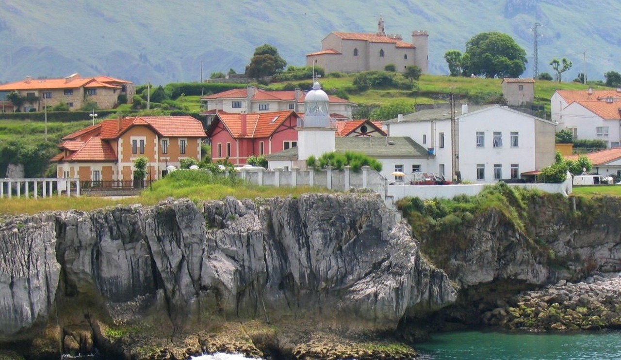 El far de Llanes sobre el penya-segat a l'entrada del port